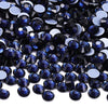 A close-up view of dark blue and black glass crystal rhinestones scattered on a white background.