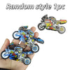 A hand holds a random style motorcycle keychain fidget toy with inertia action.
