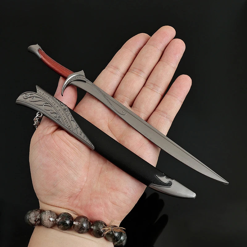 A hand holds a replica Orcrist sword, featuring a silver blade and a dark handle with a red hilt, against a black background.