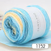 A spool of gradient rainbow yarn showing blue, yellow, and white strands rolled up on a light blue background.