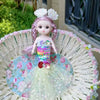 A mermaid doll with pink hair and a sequin dress sitting in a woven basket.