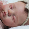 A close-up of a lifelike 19-inch reborn baby doll with soft cloth body sleeping peacefully.