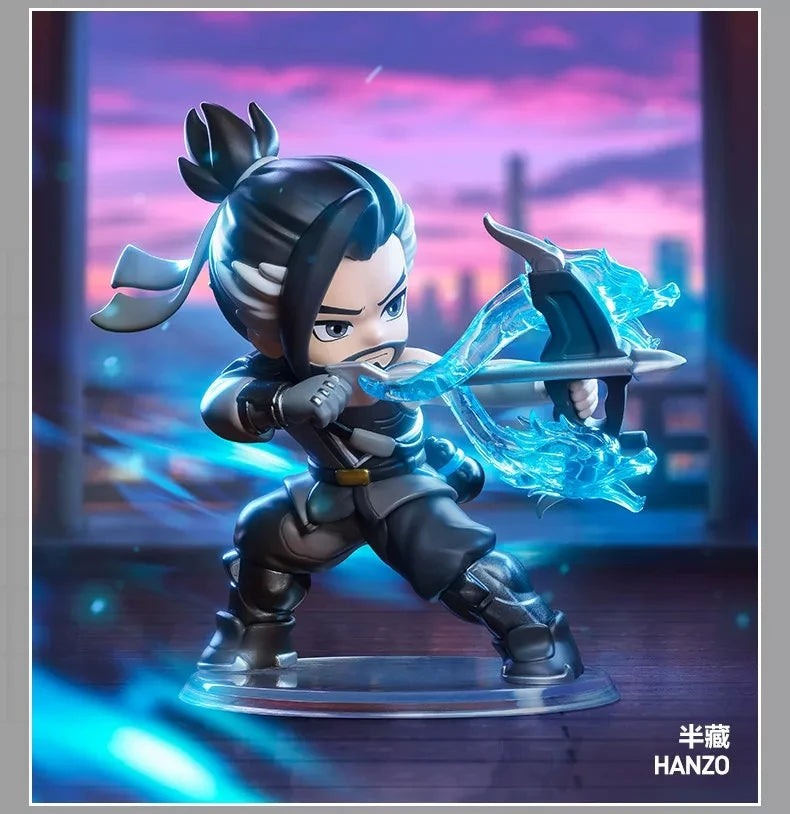 A collectible PVC figurine of Hanzo from Overwatch, featuring dark clothing and a glowing blue sword against a purple sunset 