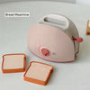 A pink bread machine is shown next to two slices of toast.