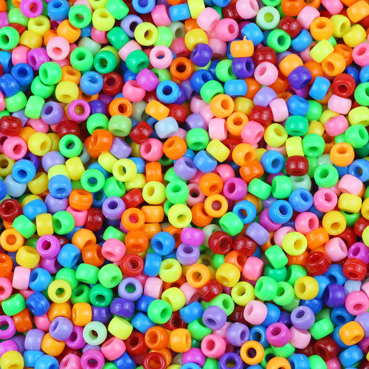 A close-up view of a large pile of solid color pony beads in various shades of pink, green, blue, and orange.