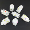 A set of seven white floral resin potion bottles shaped like polyhedral dice, arranged on a dark surface.