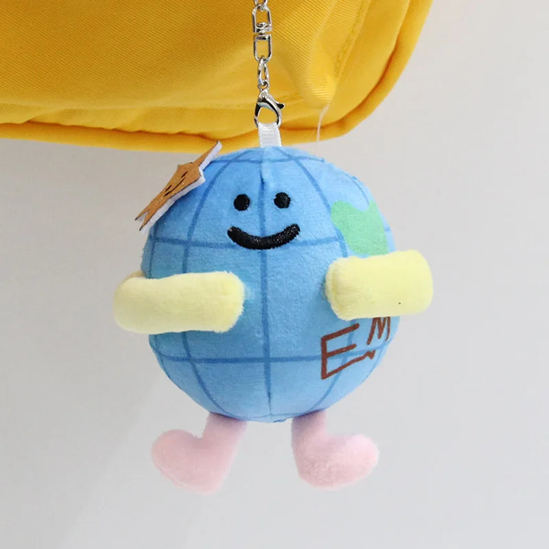 A blue plush pendant doll shaped like a globe with yellow accents and pink feet.