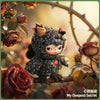 A small, dark gray plush doll resembling a creature is nestled among rose branches and leaves.