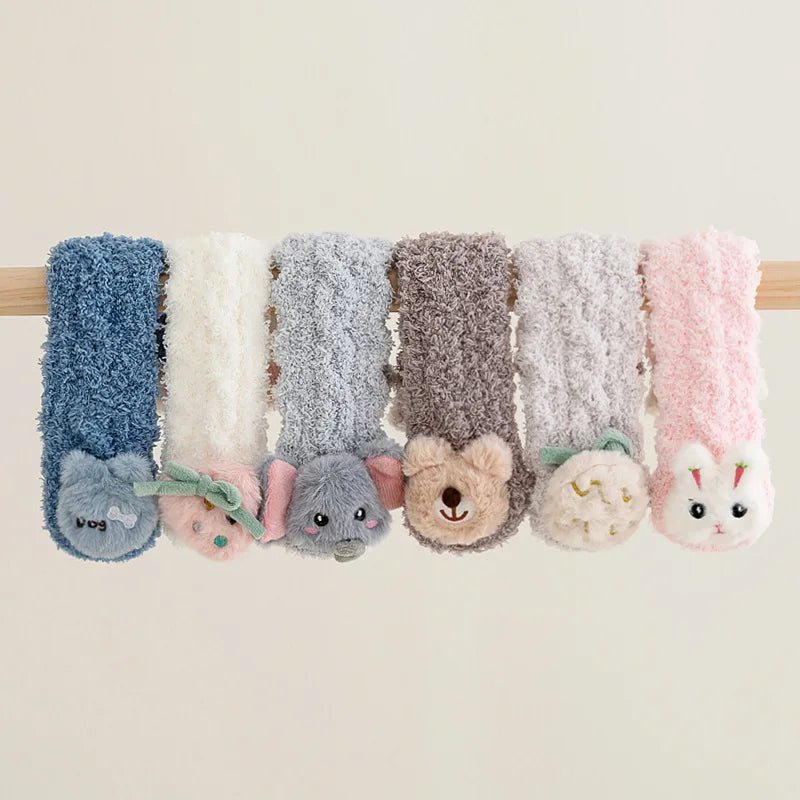 A row of plush velvet baby knee-high socks in various colors and animal faces, including blue, cream, gray, and pink.