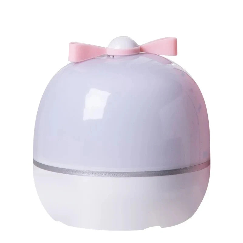 A white projector night light with a pink bow on top, featuring rotating galaxy effects.