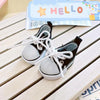 A pair of black casual sneakers with white laces and white soles resting on a wooden surface.