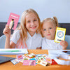 Two young girls holding colorful flash cards featuring animals and shapes for early learning