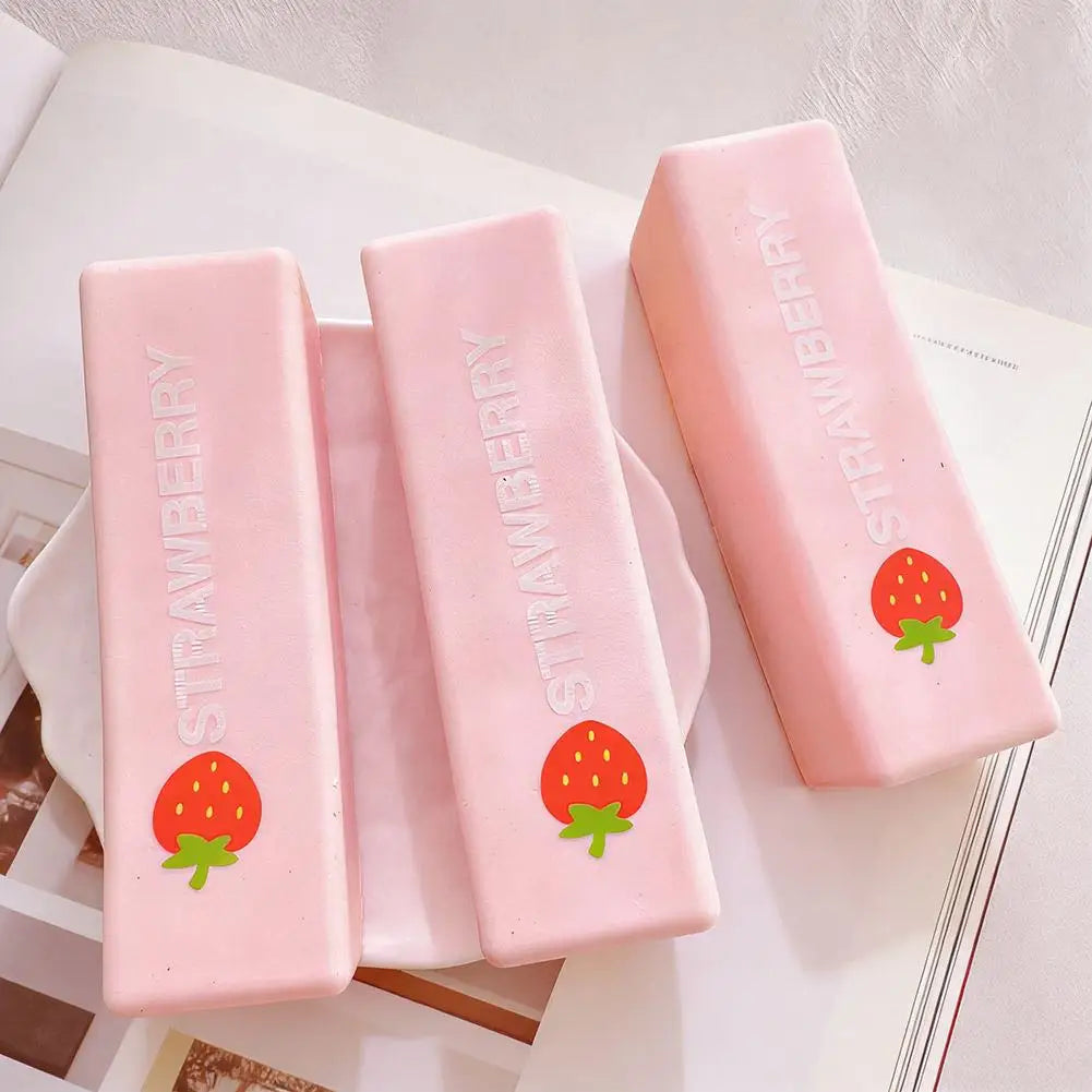 Three pink strawberry milk squishy stress relief toys standing upright on a white surface.