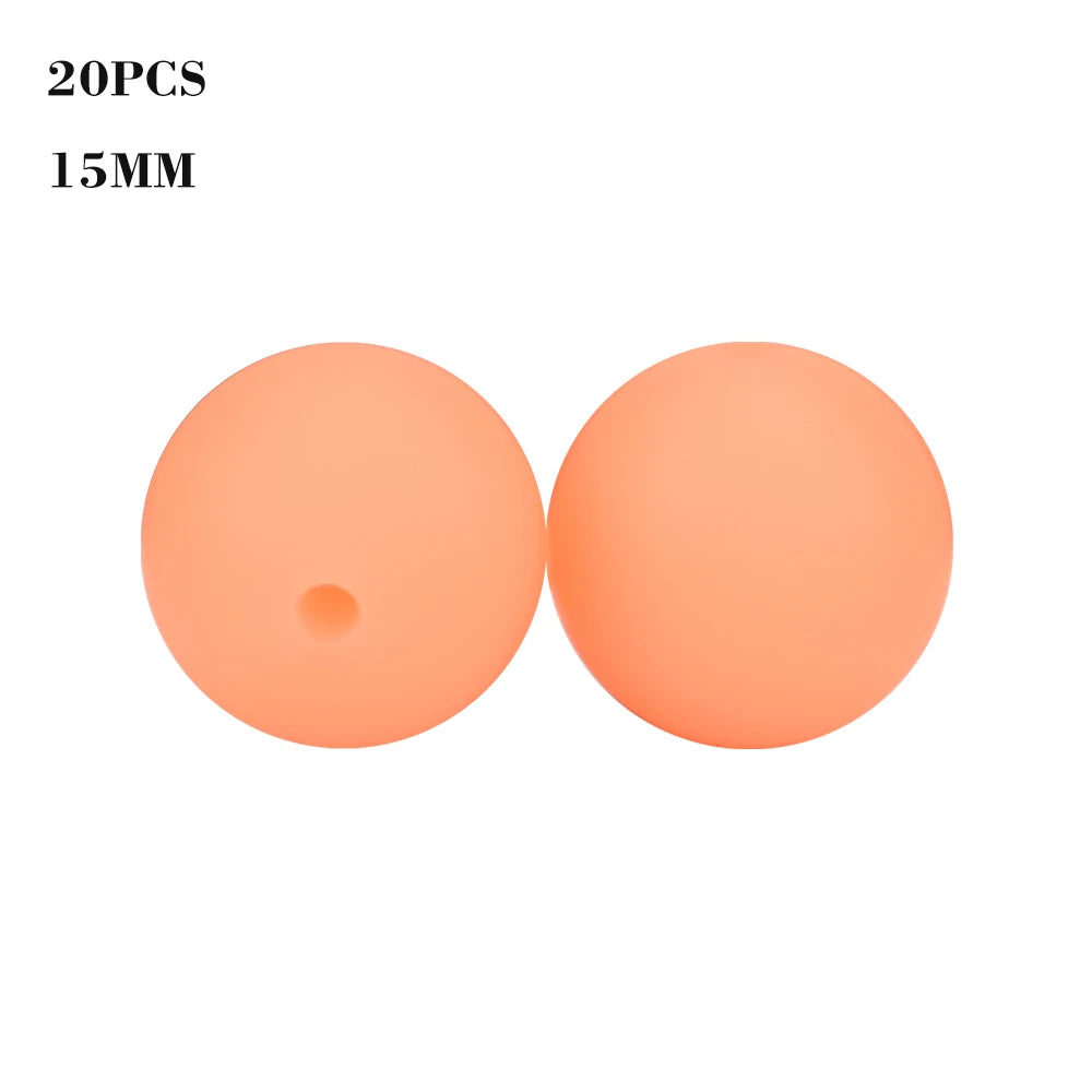 Two round, peach-colored silicone beads, 15mm in diameter, for jewelry making.