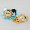 A personalized crystal pacifier and clip gift set featuring a light blue silicone pacifier and a gold-toned clip with a clear