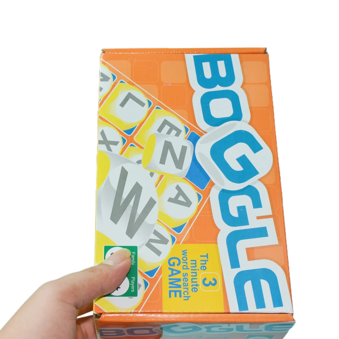 A box of Boggle The 3 Minute Word Search Dice Game with orange and blue packaging being held by a hand.