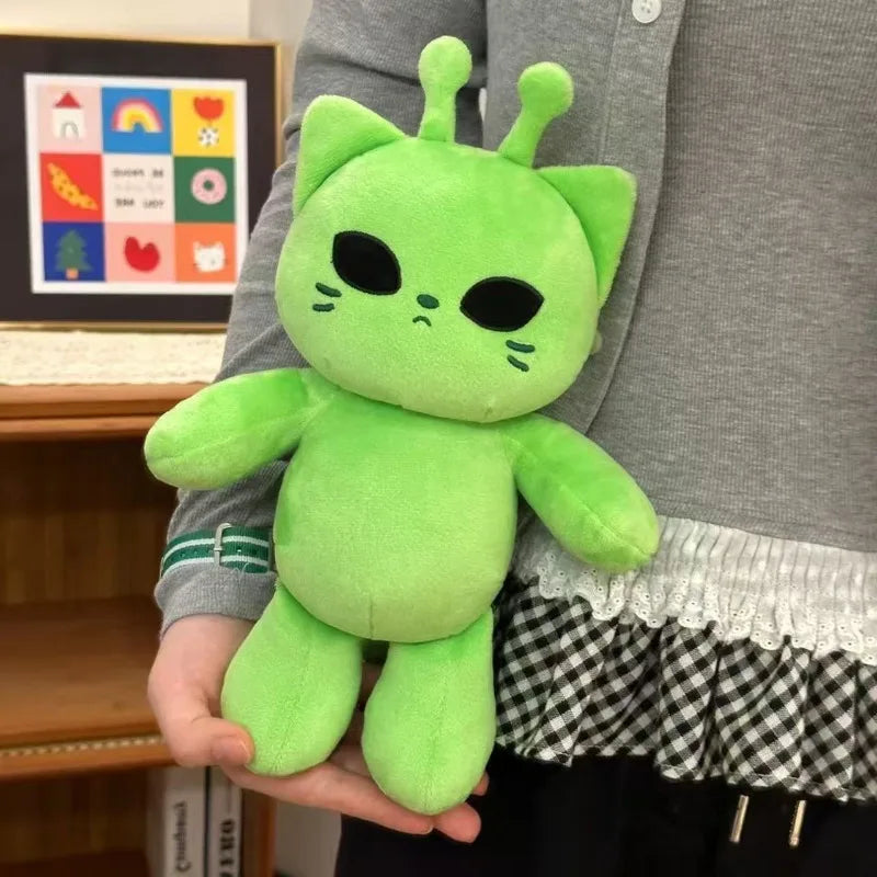 A bright green plush toy shaped like an alien cat is held in a person's hand.