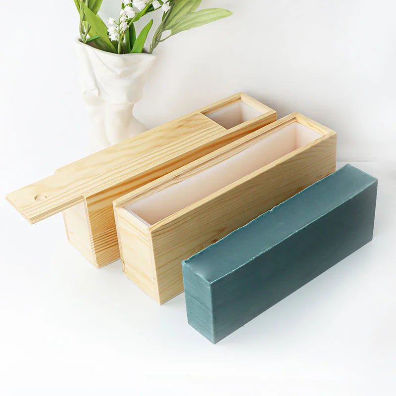 A silicone rectangle soap mold is shown with a wooden box and lid, resting on a white surface.