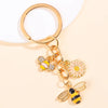 Gold-toned enamel flower keychain featuring a bee and a daisy design.