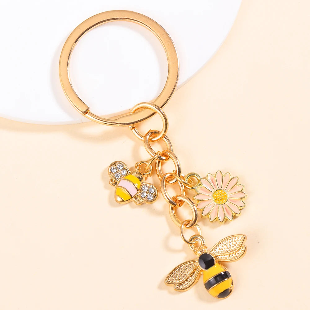 Gold-toned enamel flower keychain featuring a bee and a daisy design.