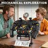A boy and a man are interacting with a mechanical exploration toy featuring a steering wheel and gears.