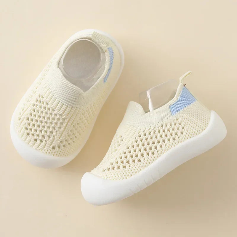 A pair of cream-colored breathable mesh slip-on sneakers for toddlers, shown from above.