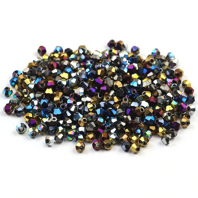 A pile of small, faceted electroplated crystal glass beads in various shades of gold, bronze, and deep blue/purple.