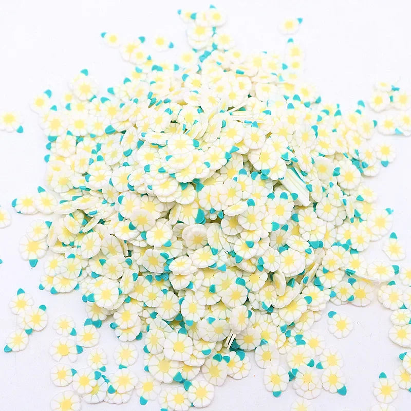 A pile of small polymer clay flower charms in white and light blue colors.