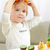 A child is shown interacting with a set of plastic fruit and vegetable models for a DIY cutting music toy.