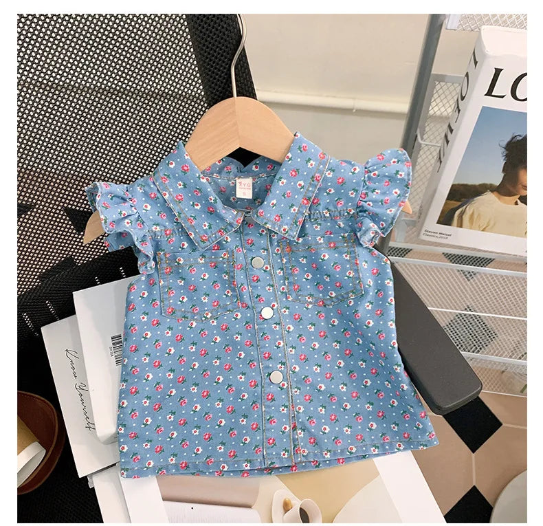 A blue floral print girls' shirt is displayed on a wooden hanger against a white background.