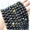 A hand holds a strand of dark, natural stone beads for DIY jewelry making.