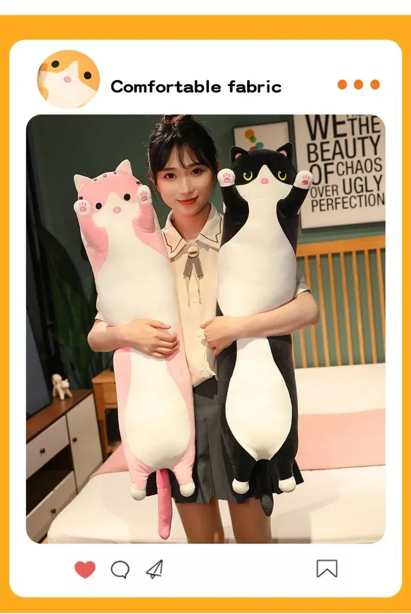 Two plush cats, one pink and one black, are being held by a woman in a bedroom setting.
