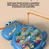 A blue plastic fish toy with a large mouth is surrounded by various magnetic fishing lures and fishing rods.