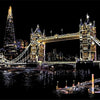 A nighttime silhouette of Tower Bridge and the London skyline illuminated with warm lights reflecting on the water.