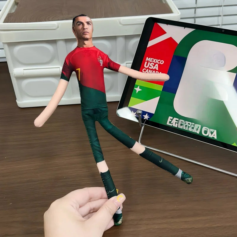 A male football star stuffed doll wearing a green and red uniform is displayed next to a digital screen showing national flag