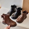 A pair of brown leather ankle boots with a bow-knot detail and side zipper resting on a white surface.