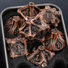 A set of seven bronze metal dice shaped like skulls and dragons resting in a dark container.