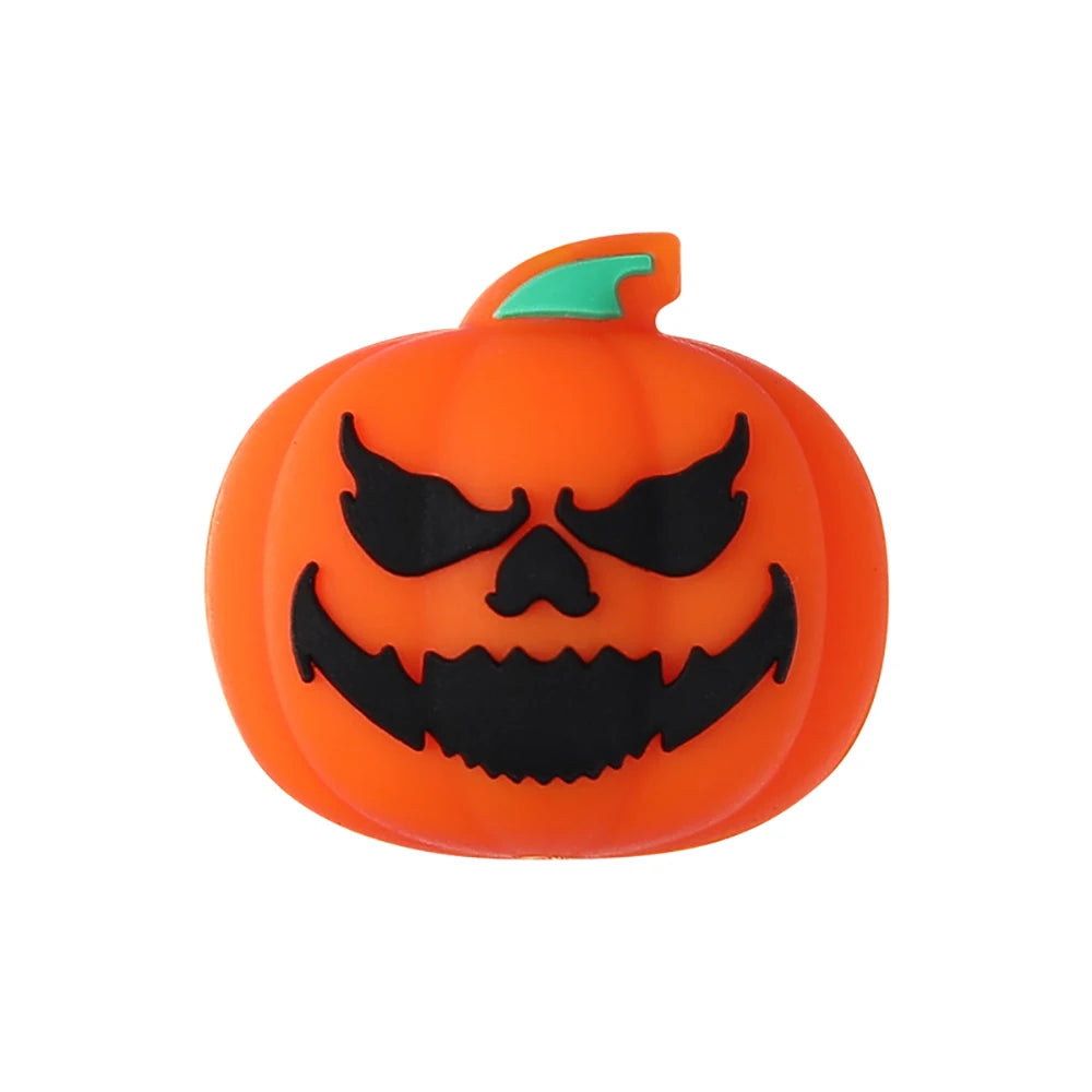 An orange silicone bead shaped like a carved pumpkin with black bat features on the face.