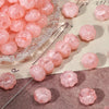 Pink gold-traced pumpkin resin beads scattered on a surface for jewelry making