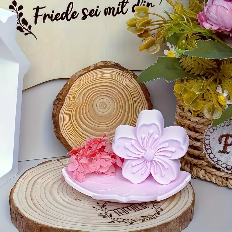 Pink silicone flower mold resting on a wooden slice with floral decorations.