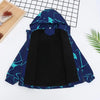 A dark blue waterproof winter jacket with a hood and geometric pattern laid out on a wooden board.
