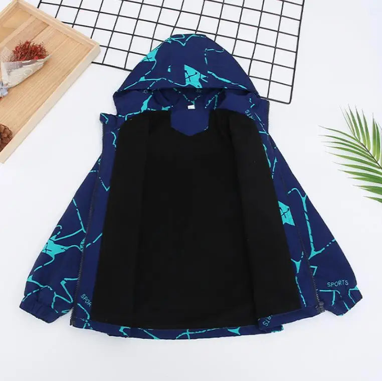 A dark blue waterproof winter jacket with a hood and geometric pattern laid out on a wooden board.