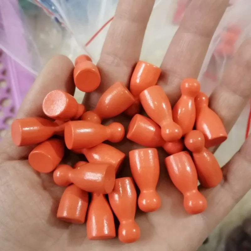 A hand holds a set of ten orange wooden chess pawns for board games.