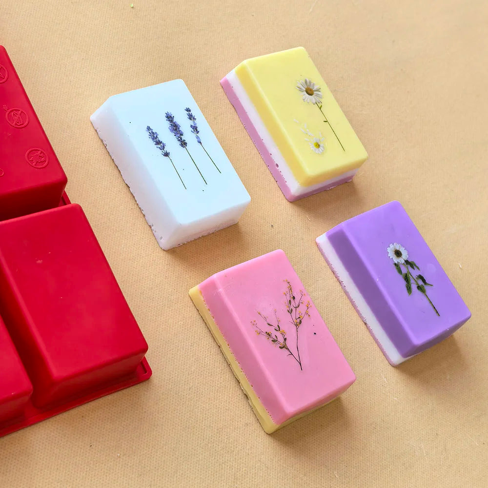 A collection of colorful silicone soap molds in various shapes and colors resting on a light brown surface.