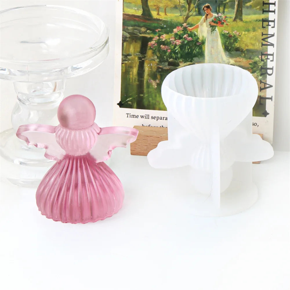 A pink silicone mold shaped like a cherub angel is displayed next to a white mold for candles or soap.