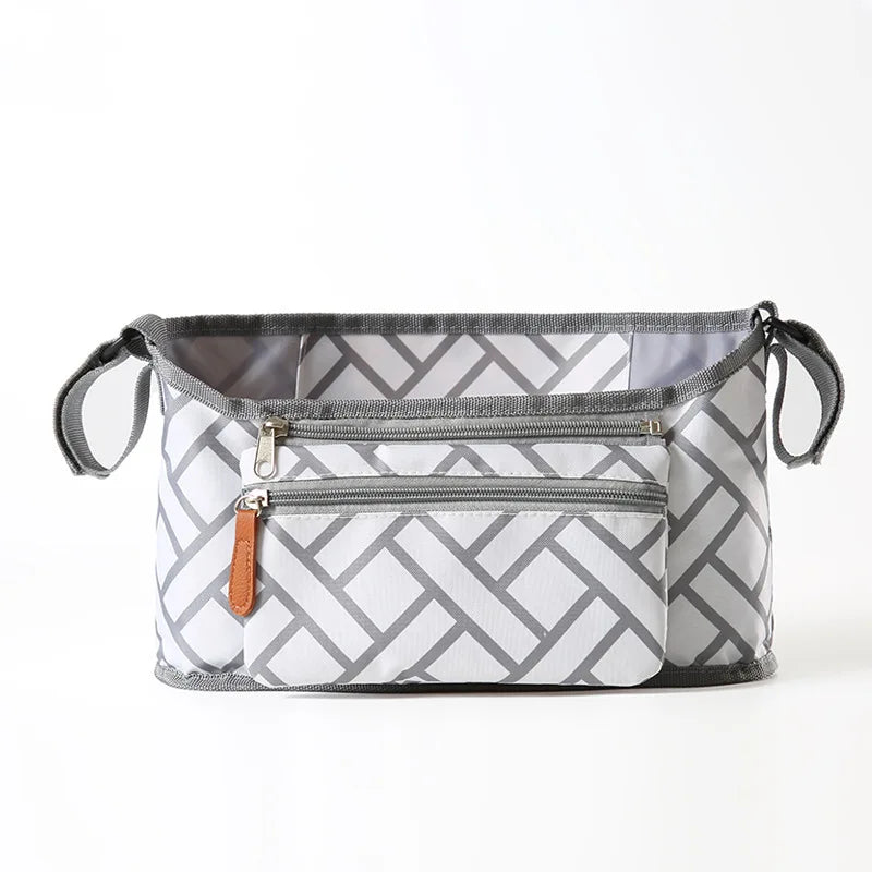 A gray and white patterned fabric organizer bag for strollers featuring zippered compartments and hanging hooks.