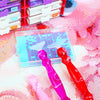A collection of diamond art pens in various colors and tips displayed on a pink textured surface.
