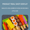 A colorful set of pretend barbecue food including sausages, corn, and other grilled items displayed on a green tray.
