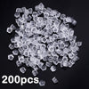 A pile of clear silicone earring backs, approximately 200 pieces, scattered on a dark surface.