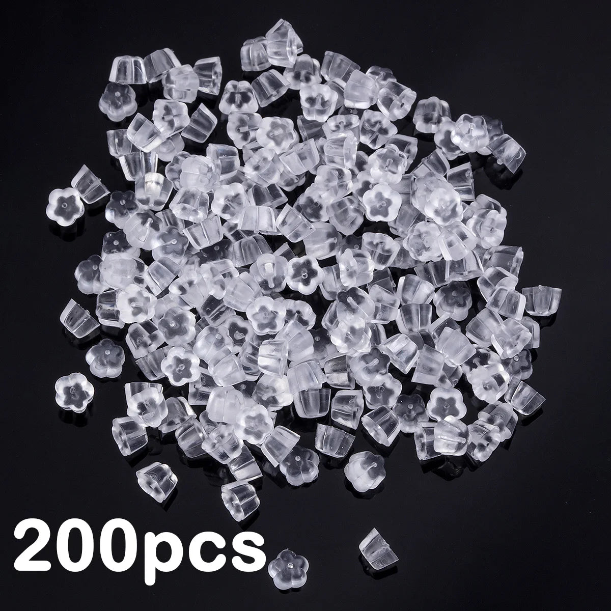 A pile of clear silicone earring backs, approximately 200 pieces, scattered on a dark surface.